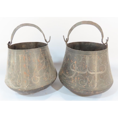 544 - A pair of tapering inlaid Arabic metalwork alms bowls with looping handles, together with a further ... 