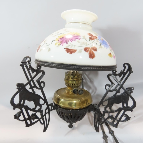 493 - A Victorian cast iron black adjustable hanging oil lamp with a floral glass shade.