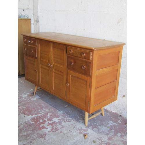 1571 - A mid 20th century Ercol sideboard, fitted with a pair of twin panelled cupboard doors flanked by pa... 