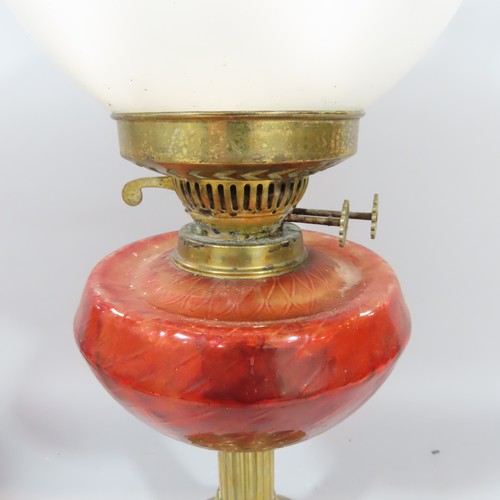 576 - Two Victorian oil lamps both with red glass fonts and brass columns.