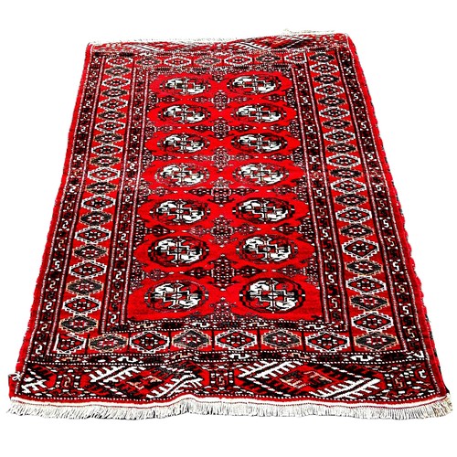 6033 - A Turkmen Bokhars rug with two rows of elephant guls on a red ground, 138cm x 98cm