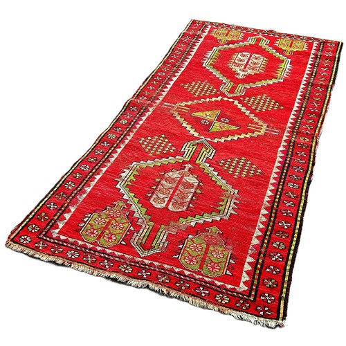 6036 - A Caucasian antique rug with triple motifs on a red ground 218 x 103 cm