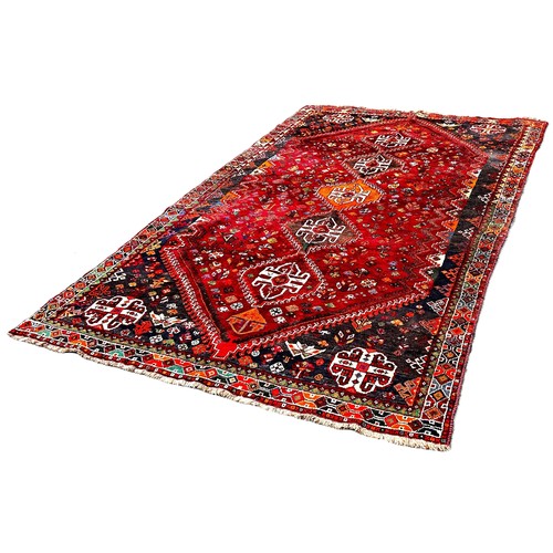 6042 - A Shiraz Gashai carpet  with a central row of interlocking medallions on red ground 260 x 177 cm app... 