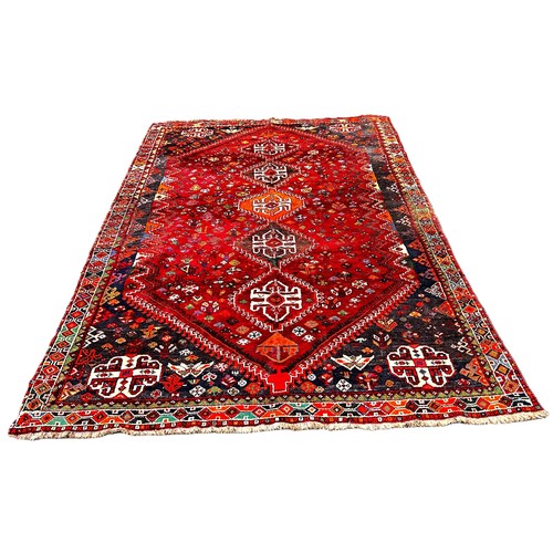 6042 - A Shiraz Gashai carpet  with a central row of interlocking medallions on red ground 260 x 177 cm app... 