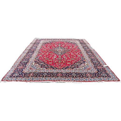 1649 - A large country house Kashan carpet with an all over floral design on a red ground with blue floral ... 