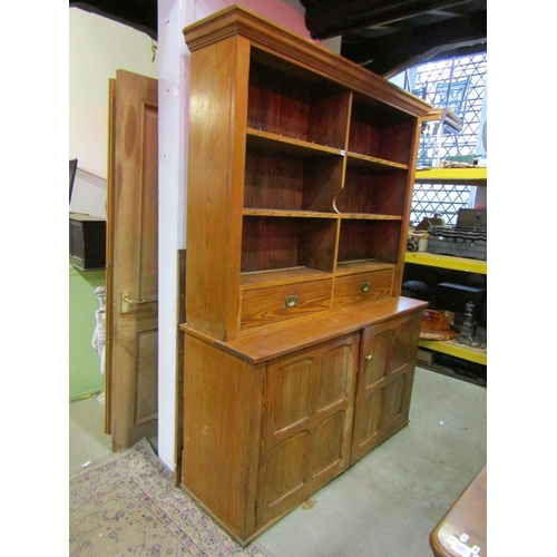 1074 - A pitch pine dresser in two sections, the lower enclosed by a pair of quarter moulded panelled doors... 