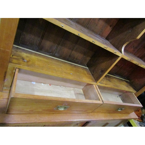 1074 - A pitch pine dresser in two sections, the lower enclosed by a pair of quarter moulded panelled doors... 