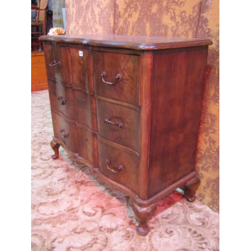 1141 - A walnut veneered serpentine front bedroom chest of three long drawers raised on squat cabriole supp... 