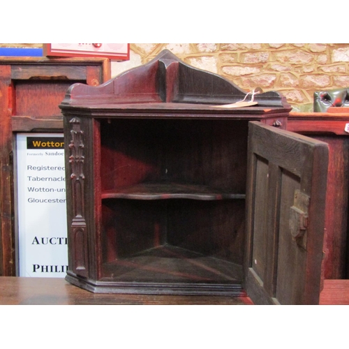 1318 - A small Gothic revival oak hanging corner cupboard, enclosed by a linenfold paneled door, with Gothi... 