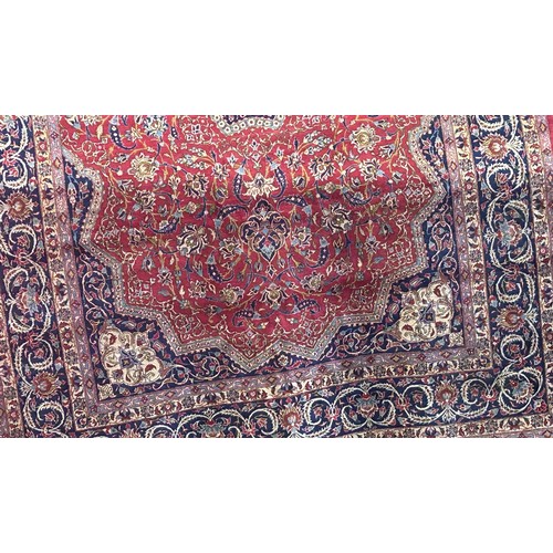 1629 - A large Middle Eastern wool carpet with a central floral medallion amongst a field of flowers on a p... 