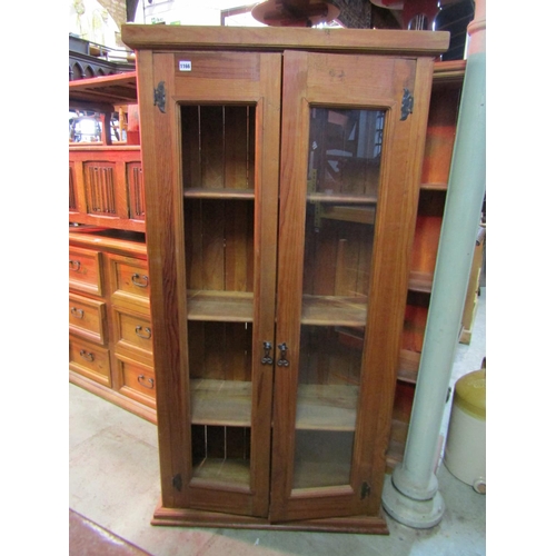 1166 - A Mexican pine floorstanding side cabinet enclosed by a pair of full length rectangular glazed panel... 