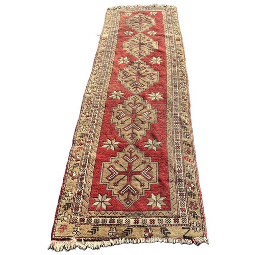 1605 - A Turkey runner with five interlocking medallions on a red ground 285cm x 90cm approximately