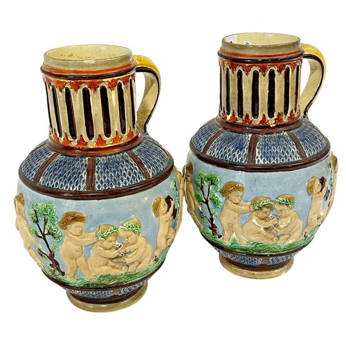 39 - A pair of continental pottery ewers, decorated with cherubs dancing, likely German, 29cm high (2)