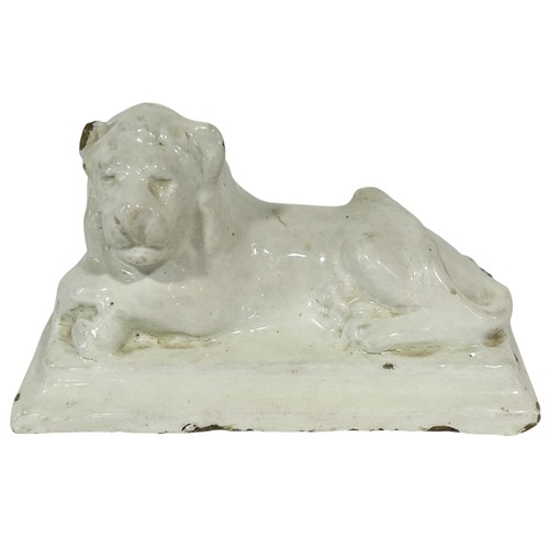 63 - A 19th century white glazed stoneware figure of a lion in a recumbent pose in, 19cm long