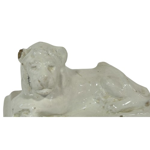 63 - A 19th century white glazed stoneware figure of a lion in a recumbent pose in, 19cm long