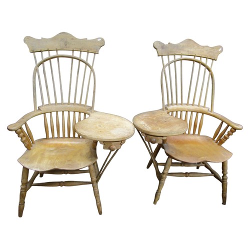 A pair of American style Windsor stick back elbow / writing chairs with dished seats and principally in ash