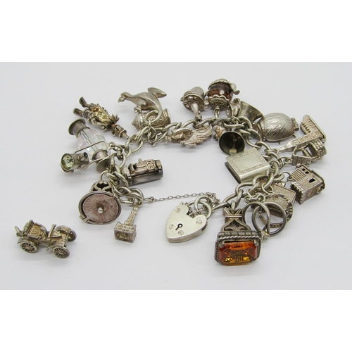 336 - Silver curb link charm bracelet with heart padlock clasp, hung with twenty-one novelty charms to inc... 