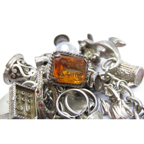 336 - Silver curb link charm bracelet with heart padlock clasp, hung with twenty-one novelty charms to inc... 