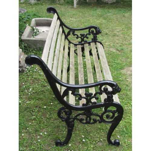 1010 - A two seat garden bench with wooden slatted seat raised on decorative cast iron end supports with op... 