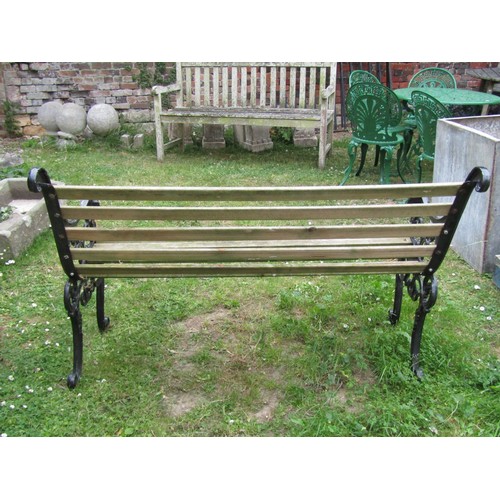 1010 - A two seat garden bench with wooden slatted seat raised on decorative cast iron end supports with op... 