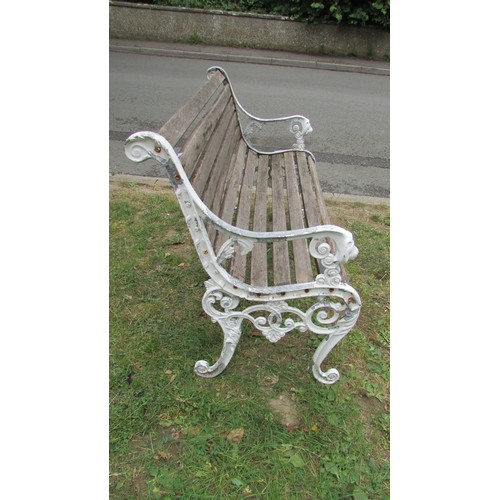 1009 - A two seat garden bench with stained and weathered slats raised on decorative painted cast alloy end... 