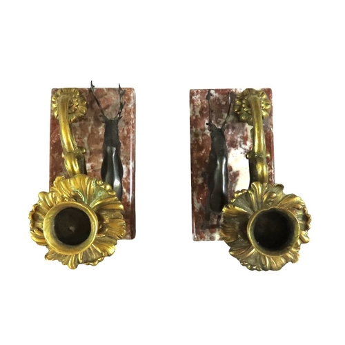 13 - A pair of 19th century continental bronze and ormolu candlesticks, decorated with opposing stags bes... 