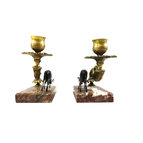 13 - A pair of 19th century continental bronze and ormolu candlesticks, decorated with opposing stags bes... 