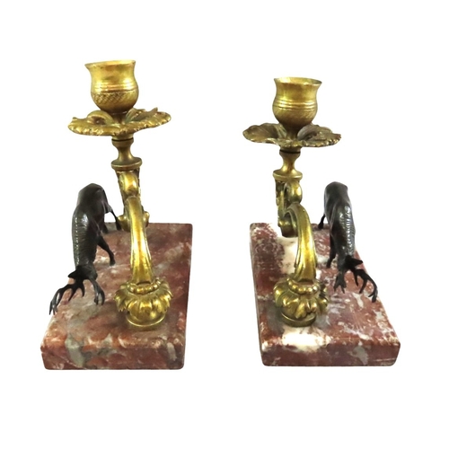 13 - A pair of 19th century continental bronze and ormolu candlesticks, decorated with opposing stags bes... 