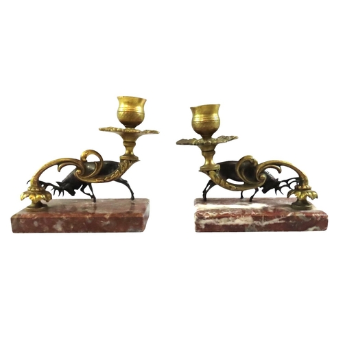 13 - A pair of 19th century continental bronze and ormolu candlesticks, decorated with opposing stags bes... 