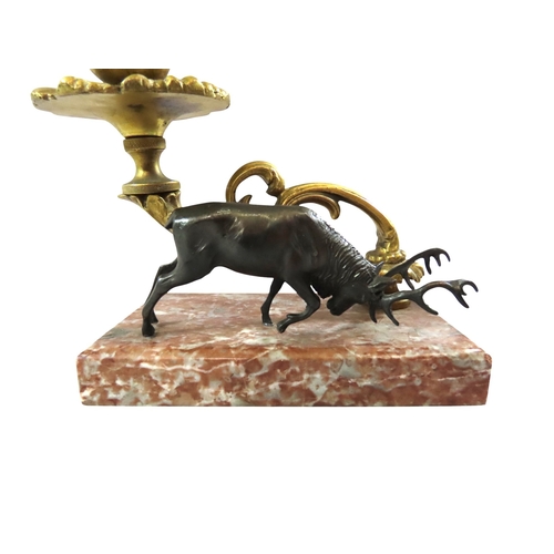 13 - A pair of 19th century continental bronze and ormolu candlesticks, decorated with opposing stags bes... 