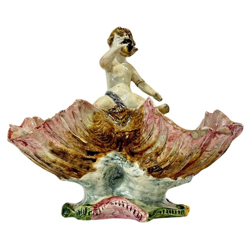 50 - A Italian Majolica table centre in the form of a young boy blowing a conch shell astride an open cla... 