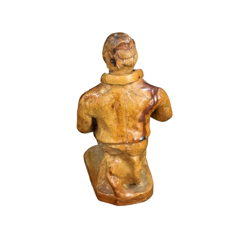 257 - An early 19th C Salt glazed figure of a seated character holding a bottle 19cm High