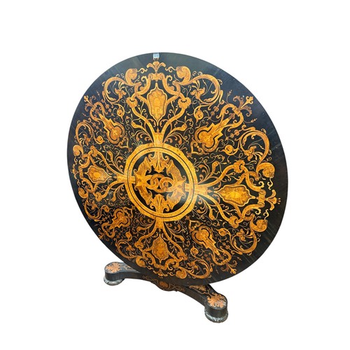 An exhibition quality centre table bearing the makers plate of George Trollope 15 & 17 Parliament St, Westminster, the circular hinged top fully inlaid with repeating geometric & other detail, raised on a vase shaped pillar & tricorn platform base with further matching inlaid detail. 141cm D X 74cm H. Original throughout. Executors instruction to sell