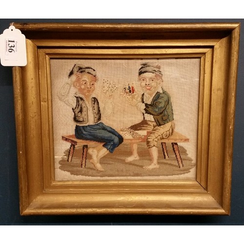 136 - A 19th Century needlework picture of two boys playing cards sitting on stools in bare feet. Con... 