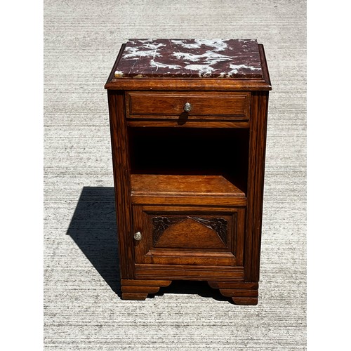 40 - A Marble topped storage unit of utilitarian design with carved decoration to the door and a lined cu... 