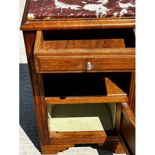 40 - A Marble topped storage unit of utilitarian design with carved decoration to the door and a lined cu... 