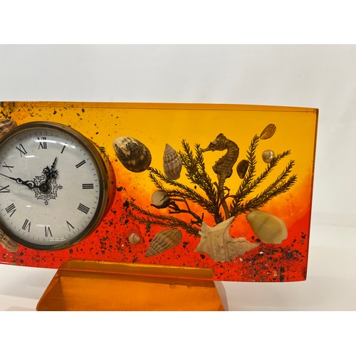 398 - Mid century mantle clock with a coloured Lucite body encapsulating sea shells etc. 19 cm x 12 cm x 2... 