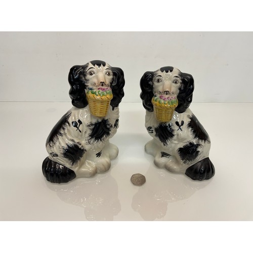 14 - A pair of Staffordshire wally dogs each holding a basket of flowers.

This lot is available for in-h... 