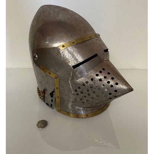 105 - A Medieval design knights helmet with weighted brass trimmings on a steel shell. 26 cm tall x 30 cm ... 