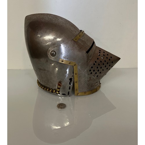 105 - A Medieval design knights helmet with weighted brass trimmings on a steel shell. 26 cm tall x 30 cm ... 