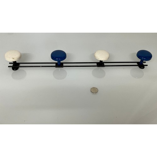 299 - Enamelled wrought iron coat pegs on a rail. 56 cm long.

This lot is available for in-house shipping