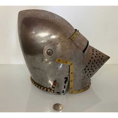 248 - A Medieval design knights helmet with weighted brass trimmings on a steel shell. 26 cm tall x 30 cm ... 