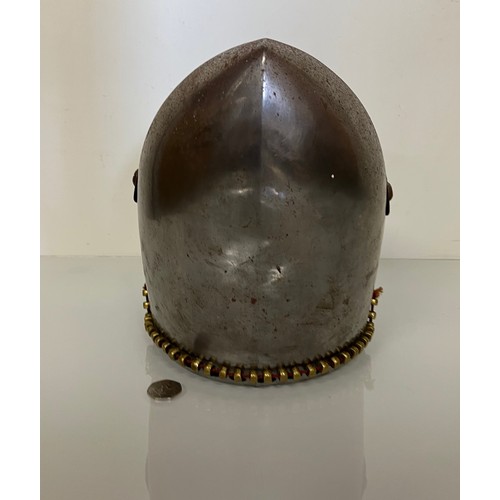 248 - A Medieval design knights helmet with weighted brass trimmings on a steel shell. 26 cm tall x 30 cm ... 