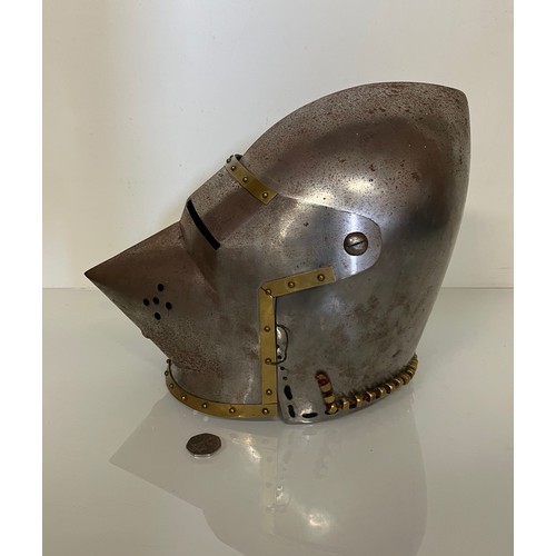 248 - A Medieval design knights helmet with weighted brass trimmings on a steel shell. 26 cm tall x 30 cm ... 