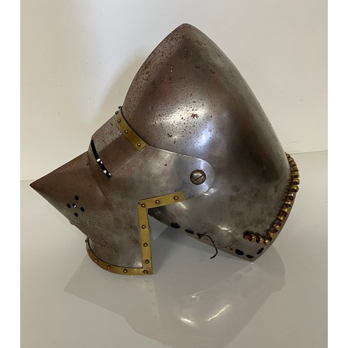 248 - A Medieval design knights helmet with weighted brass trimmings on a steel shell. 26 cm tall x 30 cm ... 