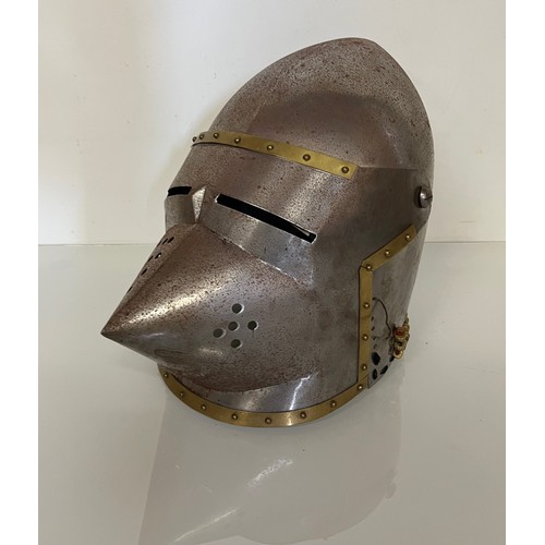 248 - A Medieval design knights helmet with weighted brass trimmings on a steel shell. 26 cm tall x 30 cm ... 