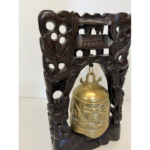 249 - Oriental temple bell, a cast bell decorated with dragons supported within a carved hard wood stand w... 