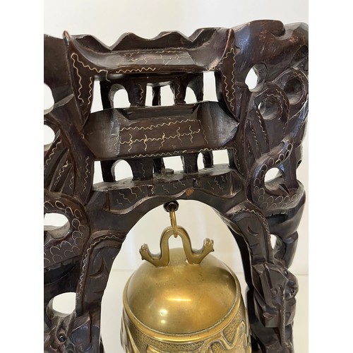 249 - Oriental temple bell, a cast bell decorated with dragons supported within a carved hard wood stand w... 