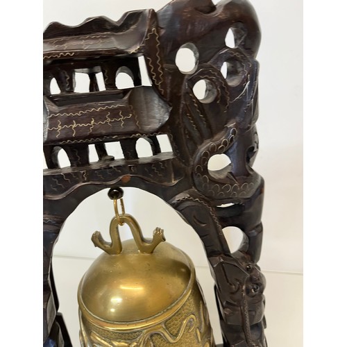 249 - Oriental temple bell, a cast bell decorated with dragons supported within a carved hard wood stand w... 