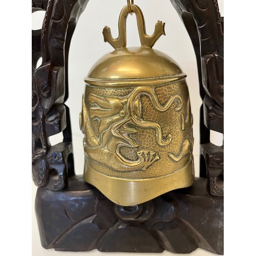 249 - Oriental temple bell, a cast bell decorated with dragons supported within a carved hard wood stand w... 